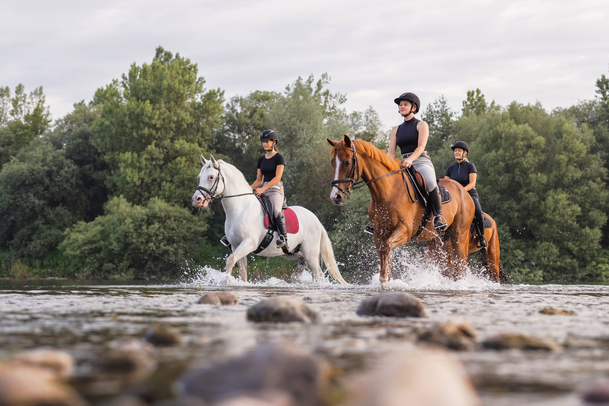 Tre ragazze a cavallo attraversano fiume 